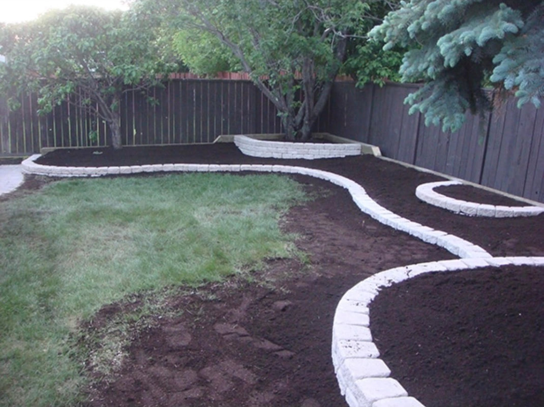 green backyard lawn with neat white retaining wall