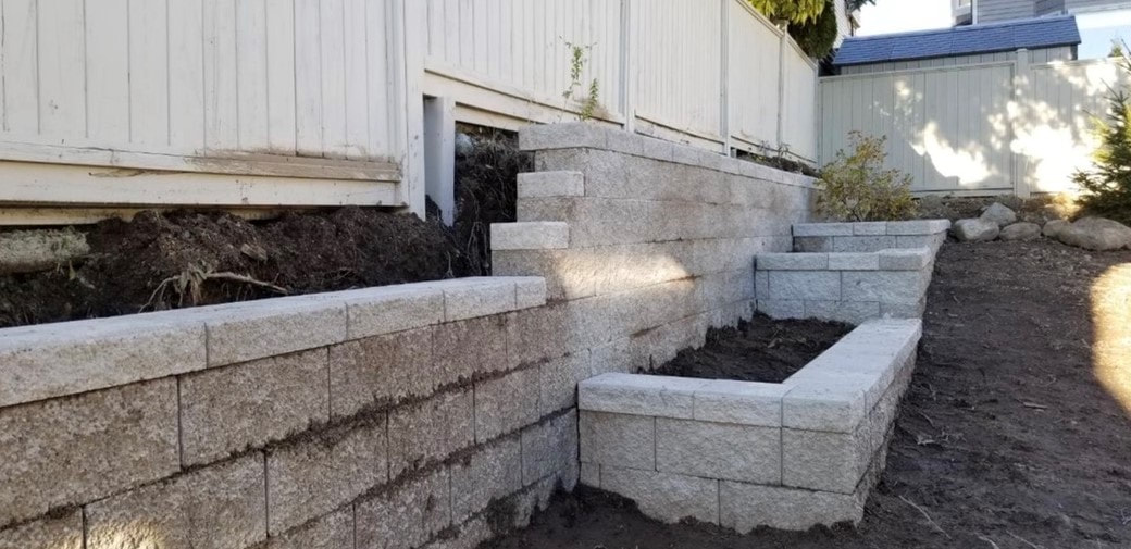 retaining wall and planters along white fence