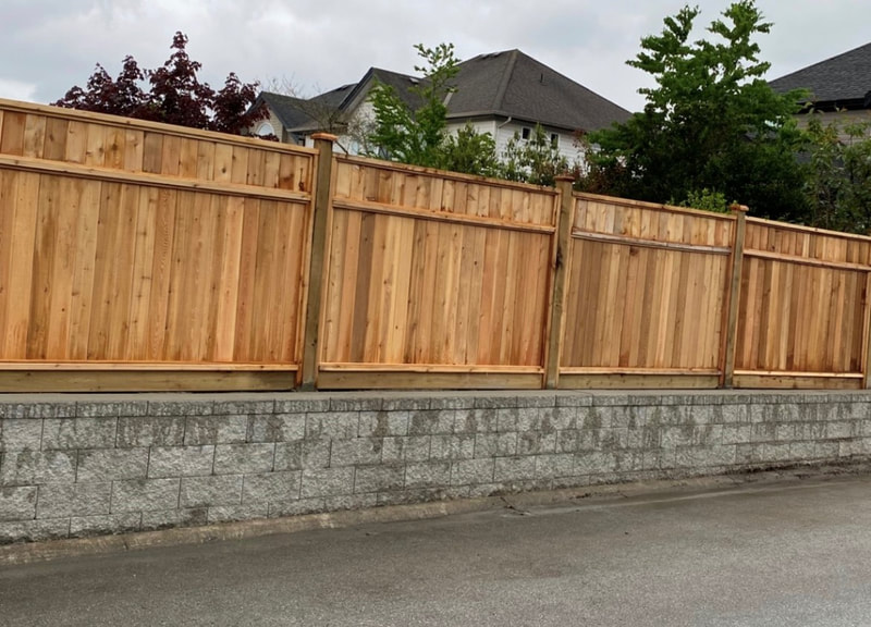 wooden fence on top of grey retaining wall